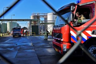 Afbeelding bij onderzoek Brandweerzorg in de Amsterdamse haven. Een terrein waarop twee brandweerauto's staan